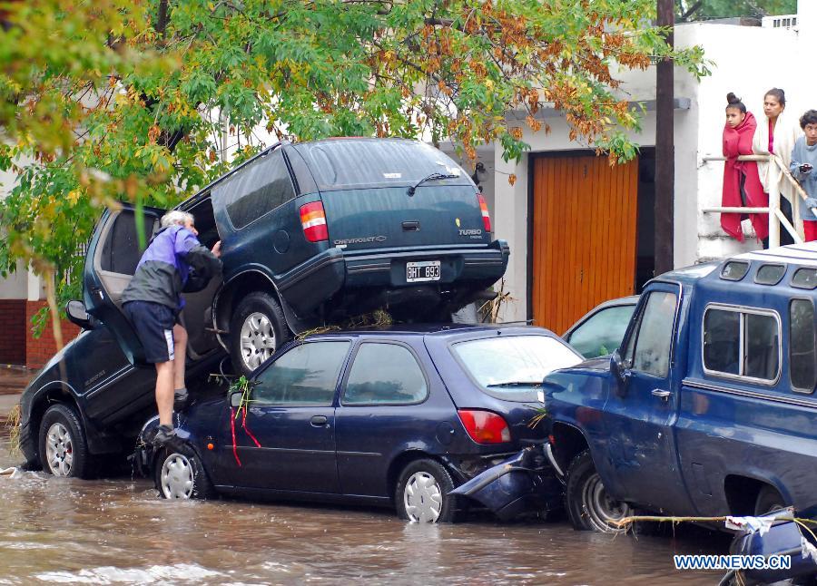 A person tries to get into a car stranded in a flooded area, after a storm, in La Plata, 63 km south of Buenos Aires, Argentina, on April 3, 2013. (Xinhua/TELAM) 