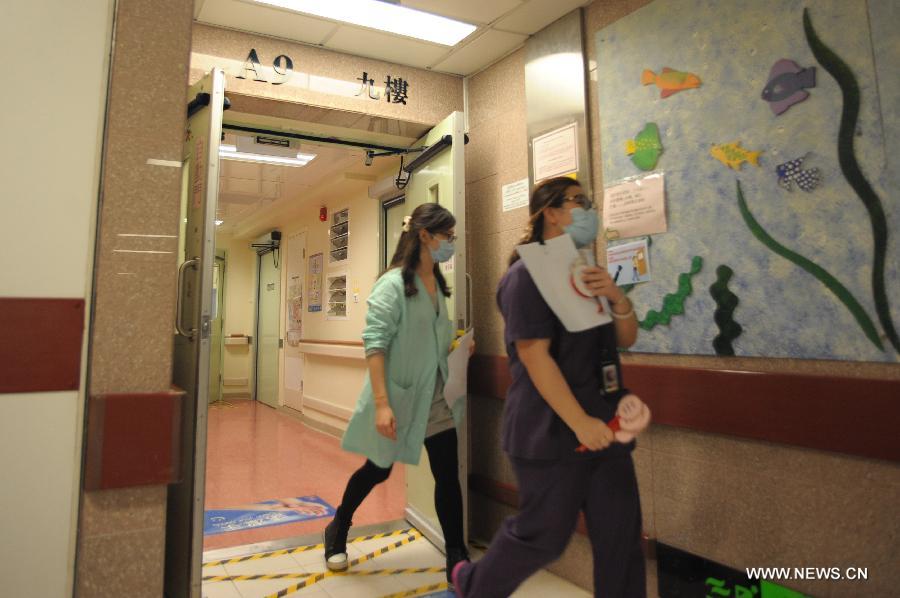 Health workers leave the A9 isolation wards at the Queen Elizabeth Hospital in Hong Kong, south China, April 5, 2013. An offcial of Hong Kong's Hospital Authority said on Friday that a seven-year-old girl in Hong Kong was reported the symptom of fever and received treatment at the Queen Elizabeth Hospital, who had been in close contact with birds in Shanghai last month. And the result whether she is infected with H7N9 virus is expected to come out Friday night. (Xinhua/Lui Siu Wai)