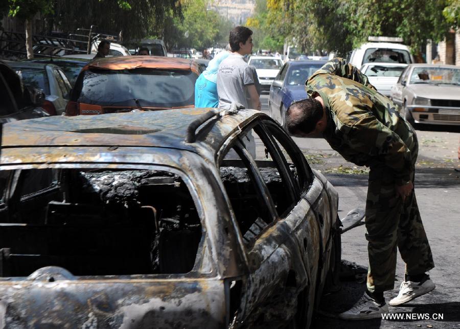 A soldier inspects a damaged car after mortar attacks in Damascus, Syria, April 6, 2013. Multiple mortar shells struck on Saturday several areas of Syria's capital Damascus, including a stadium and the building of the state-run al-Thwara newspaper, a pro-government radio reported. (Xinhua/Zhang Naijie) 