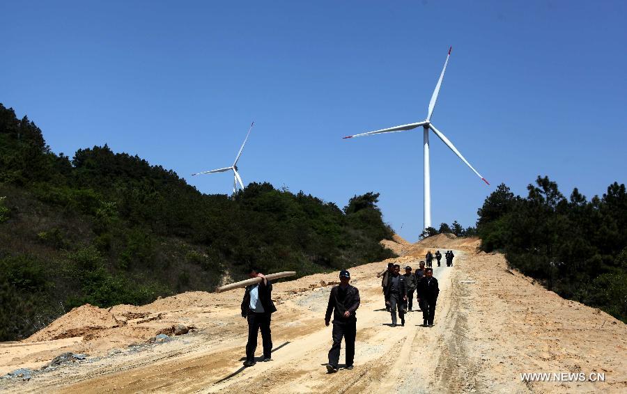 People walk on a road near the Bijiashan Wind Power Plant beside the Poyang Lake in Jiujiang City, east China's Jiangxi Province, April 7, 2013. The Bijiashan Wind Power Plant, invested by China Power Investment Corporation, has been put into operation with 48 megawatts of installed generating capacity. Currently, there are five wind power plants around the Poyang Lake, respectively Jishanhu, Changling, Daling, Laoyemiao and Bijiashan. (Xinhua/Fu Jianbin) 