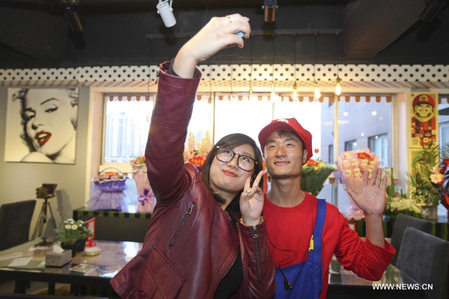 A waiter in the costume of Super Mario, a famous video game character, poses for photos with a customer at a Mario themed restaurant in Tianjin, north China, April 8, 2013. The restaurant that opened on Monday attracted many young customers due to its "Mario-like" waiters and various decorations. (Xinhua/Fu Wenchao)