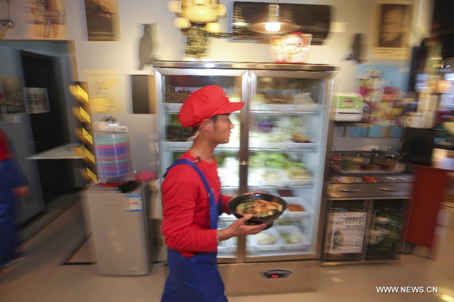 A waiter in the costume of Super Mario, a famous video game character, serves dishes at a Mario themed restaurant in Tianjin, north China, April 8, 2013. The restaurant that opened on Monday attracted many young customers due to its "Mario-like" waiters and various decorations. (Xinhua/Fu Wenchao) 