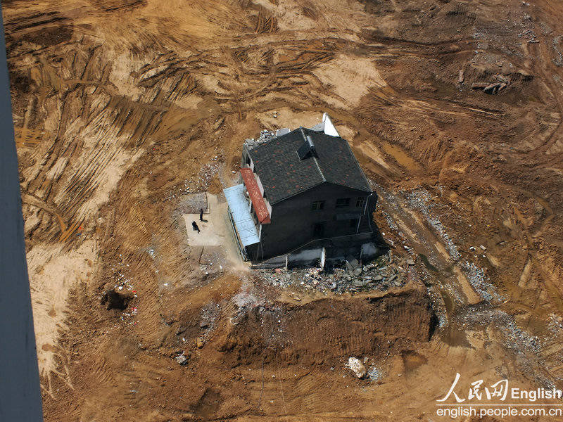 A "nail house" remains standing at a construction site in Gongqin village of Yichang city, Central China's Hubei province, April 8, 2013. A nail house is a Chinese term for homes whose owners refuse to move to make room for property development. Usually the homeowners can't come to an agreement with developers about compensation. Over the past year, power and water supplies to this house were repeatedly cut off in anonymous attacks at night. [Photo/CFP]