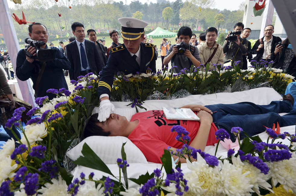 A pallbearer adjusts the clothes for an experiencer in Wuhan, Central China's Hubei province, March 30, 2013. The faux funeral aimed to make people think about life and find their true self. (Xinhua Photo)