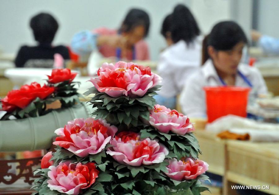 Workers process porcelain products of peony at a ceramic factory in Luoyang, central China's Henan Province, Oct. 29, 2012. Known as the "city of peony", Luoyang has created an industry chain on peony in recent years. Various crafts and products of peony have been developed to serve the local economy. (Xinhua/Wang Song)