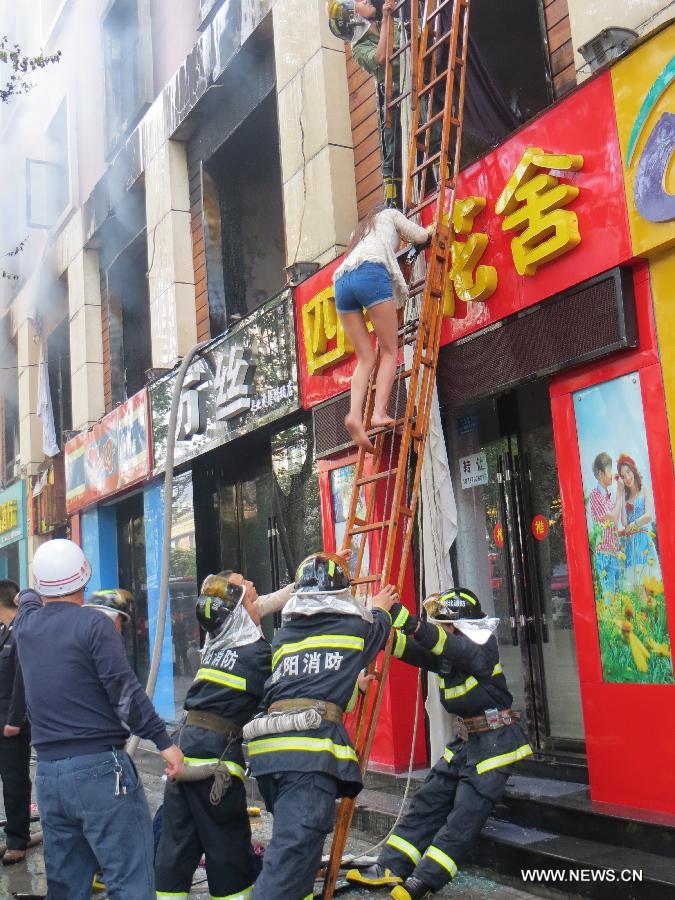 Firefighters help a woman to escape from the accident site after a fire broke out in a hotel in the Fancheng District of Xiangyang City, central China's Hubei Province, April 14, 2013. Fourteen people have been confirmed dead and 50 others injured in the hotel fire that occurred on Sunday morning. (Xinhua)