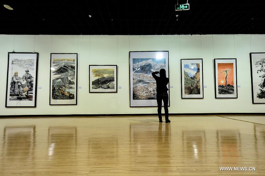 A visitor takes pictures of paintings at an exhibition commemorating the third anniversary of the Yushu earthquake, at the Qinghai Provincial Museum in Xining, capital of northwest China's Qinghai Province, April 14, 2013. A 7.1-magnitude earthquake hit Yushu on April 14, 2010, leaving 2,698 dead and over 12,000 injured.(Xinhua/Wu Gang) 