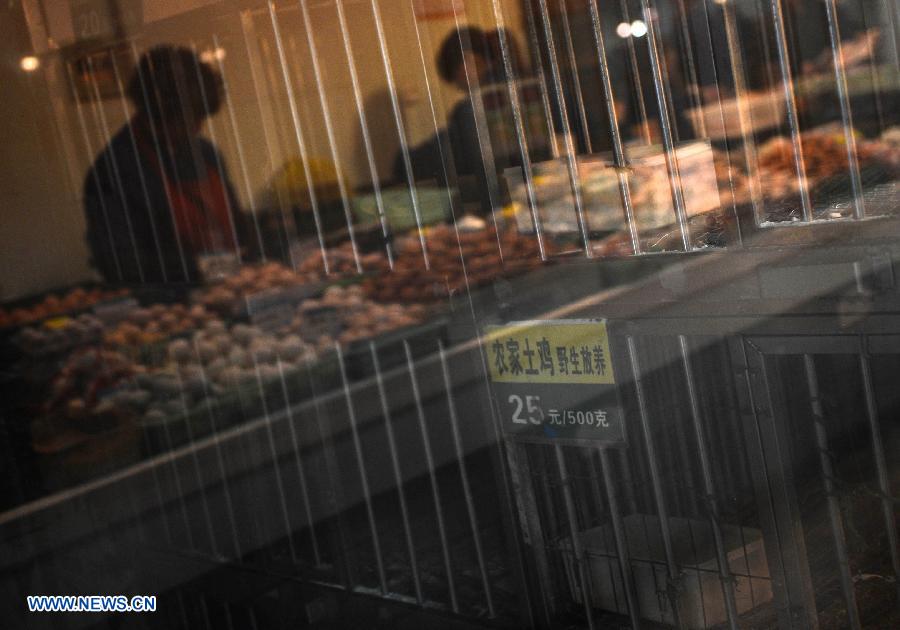 A piece of glass refects empty chicken coops and traders only sell eggs in a fowl trade area at a market in Hangzhou, capital of east China's Zhejiang Province, April 15, 2013. The city banned all trade of live fowl and closed its bird markets in its main urban areas to avoid infection of H7N9 avian flu, according to the city's announcement on April 14. (Xinhua/Han Chuanhao)