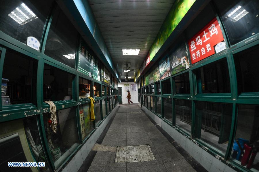 A person walks past empty chicken coops in a fowl trade area at a market in Hangzhou, capital of east China's Zhejiang Province, April 15, 2013. The city banned all trade of live fowl and closed its bird markets in its main urban areas to avoid infection of H7N9 avian flu, according to the city's announcement on April 14. (Xinhua/Han Chuanhao)
