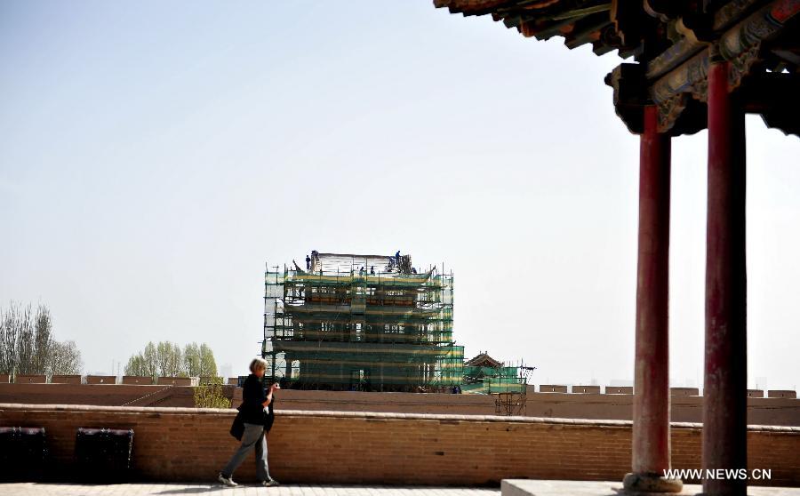 A tourist walks past the Jiayu Pass, the starting point of a section of the Great Wall constructed during the Ming Dynasty (1368-1644), in Jiayuguan City, northwest China's Gansu Province, April 16, 2013. China will pour 2.03 billion yuan (about 328 million US dollars) in maintaining the Jiayu Pass, also including the construction of a world culture heritage inspection center and a heritage protection and display project. Built in 1372, the Jiayu Pass also served as a vital passage on the ancient Silk Road. It was listed on UNESCO's World Heritage List in 1987. (Xinhua/Lian Zhenxiang) 