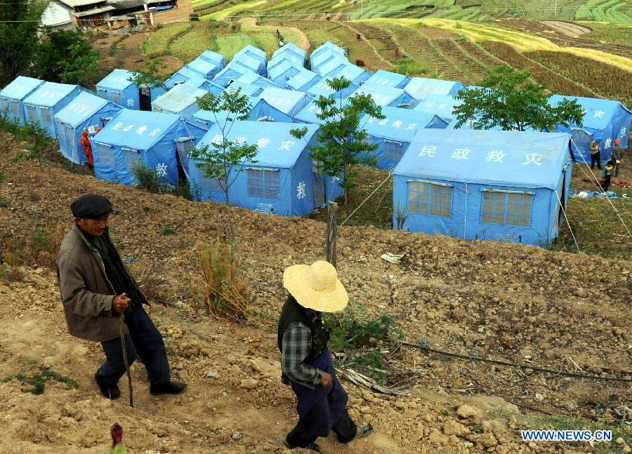 Local villagers walk past their shelter tents at a settlement site at Changyi Village of Liantie Township in Eryuan County under Dali Bai Autonomous Prefecture, southwest China's Yunnan Province , April 17, 2013. A 5-magnitude earthquake jolting Dali Wednesday morning has affected 123,000 people. (Xinhua/Chen Haining)