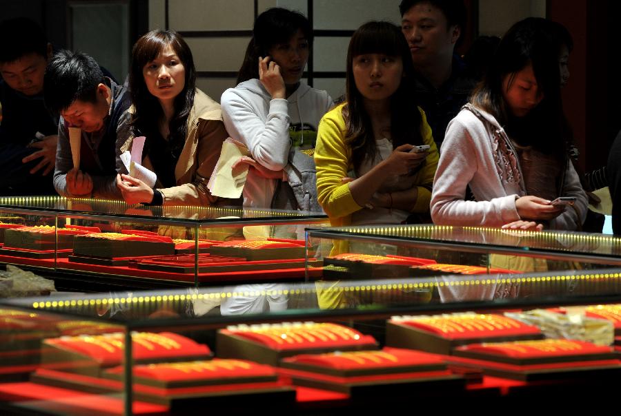Consumers wait in a line to check out at a gold jewellery shop in Nanjing, capital of east China's Jiangsu Province, April 18, 2013. Gold jewellery shops through China have lowered price of gold jewellery due to the consecutive decline of gold price global markets recently, which boost sales in these shops. (Xinhua) 