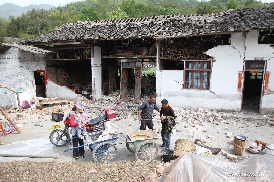 Residents stand outside of their damaged houses after a 7.0-magnitude earthquake in Longmen Township, Lushan County, Ya'an City of southwest China's Sichuan Province, April 20, 2013. At least 102 people were killed in the earthquake in Sichuan, according to the China Earthquake Administration on Saturday afternoon. (Xinhua/Zhang Xiaoli)  