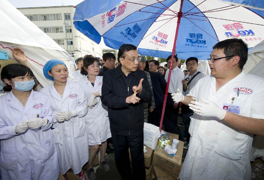 Chinese Premier Li Keqiang (C), also a member of the Standing Committee of the Political Bureau of the Communist Party of China Central Committee, inquires about victim rescue situation in the local hospital of the quake-hit Lushan County, southwest China's Sichuan Province, April 20, 2013. Li Keqiang arrived in Sichuan Saturday afternoon to deploy quake relief work. (Xinhua/Huang Jingwen)