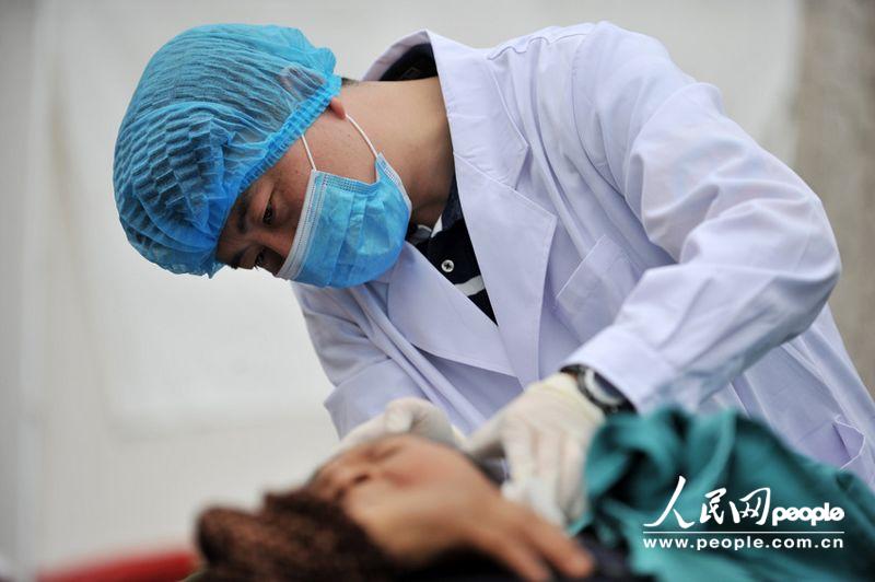 A doctor gives treatment to a wounded in the People's Hospital in Lushan, Sichuan province, April 21, 2013. More than 3,000 people had been sent here to get treatment as of 11:30 a.m. of April 21, 2013. (Weng Qiyu/People’s Daily Online)