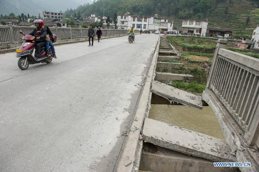People pass on a damaged bridge leading to the severely-hit Baosheng Town of Lushan County in Ya'an City, southwest China's Sichuan Province, April 21, 2013. A 7.0-magnitude earthquake jolted Lushan County on April 20 morning. Aftershocks continued to rock the region. (Xinhua/Chen Cheng)
