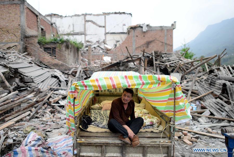 Yang Mingbo, a displaced resident, sits in a makeshift tent in Taiping Town, Lushan County, southwest China's Sichuan Province, April 21, 2013. Military and civilian rescue teams are struggling to reach every household in Lushan and neighboring counties of southwest China's Sichuan Province, badly hit by Saturday's strong earthquake. (Xinhua/Jiang Hongjing) 