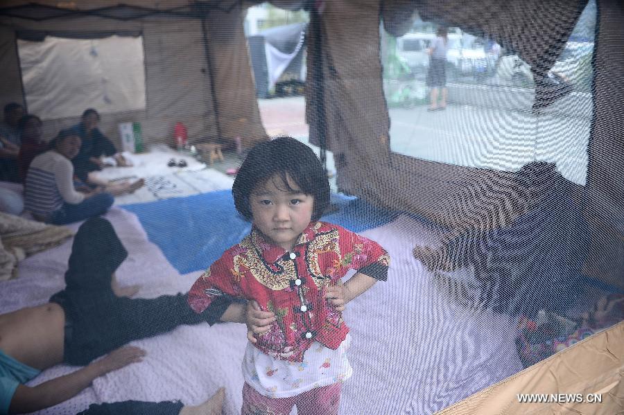 Four-year-old girl Yang Huiying stands inside a tent at a temporary settlement site in the quake-hit Lushan County, southwest China's Sichuan Province, April 21, 2013. (Xinhua/Zhang Hongxiang) 