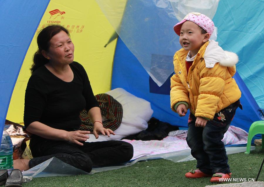 Two-year-old boy Zhu Ziwei dances for his grandmother outside a tent in the quake-hit Baoxing County, southwest China's Sichuan Province, April 22, 2013. (Xinhua/Pei Xin)