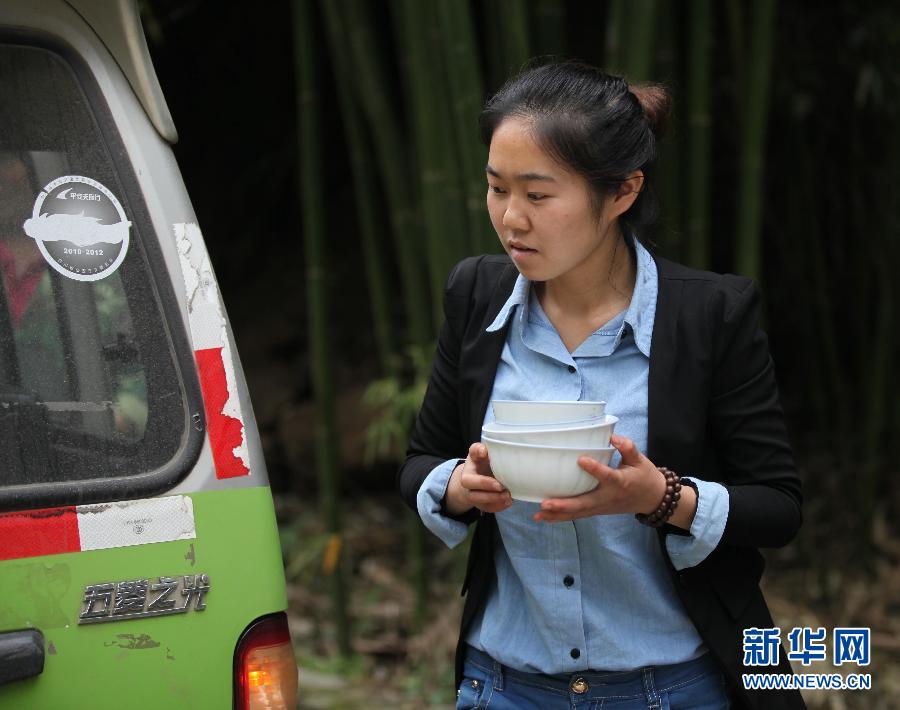 Yue Yan, 23, collects bowls from rescuers after they finish their meals in Lushan county, April 22, 2013. Yue has been serving food to quake rescuers after her hometown was jolted on Saturday. She returned home from her college in Chengdu, capital of Sichuan, to provide rescue workers with food from her home. Her family home has been destroyed by the disaster and her parents have had to spend their nights in a truck.(Zhang Xiaoli/Xinhua)