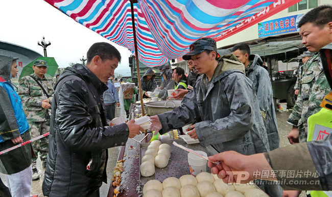 Soldiers serve local people with cooked food at a food supply point in the quake-hit Lushan County in southwest China's Sichuan Province on April 23, 2013. The Joint Logistics Department of the Chengdu Military Area Command of the Chinese People's Liberation Army set in the towns of the Lushan County mostly severely-hit by earthquake supply points to provide hot cooked food for villagers whose homes were ruined in the 7.0-magnitude earthquake occurring in the Lushan County on April 20, 2013. (PLA Daily/Qiao Tianfu)