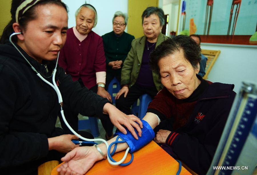 A community worker does blood pressure check for an old woman in Jin'an District of Fuzhou, capital of southeast China's Fujian Province, April 27, 2013. A total of 435 community service centers have been set up in Fuzhou since 2008 to provide daily care and entertainment activities for senior citizens. (Xinhua/Zhang Guojun)