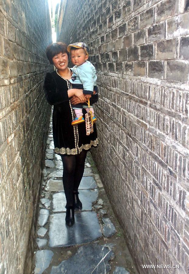 A woman carries a child as they pass through a lane in Sanhe Town of Feixi County, east China's Anhui Province, April 24, 2013. The Sanhe Ancient Town, which has a history of more than 2,500 years, is a typical "ancient town full of rivers and lakes, together with small bridges, flowing water and local dwellings." (Xinhua/Wang Song)