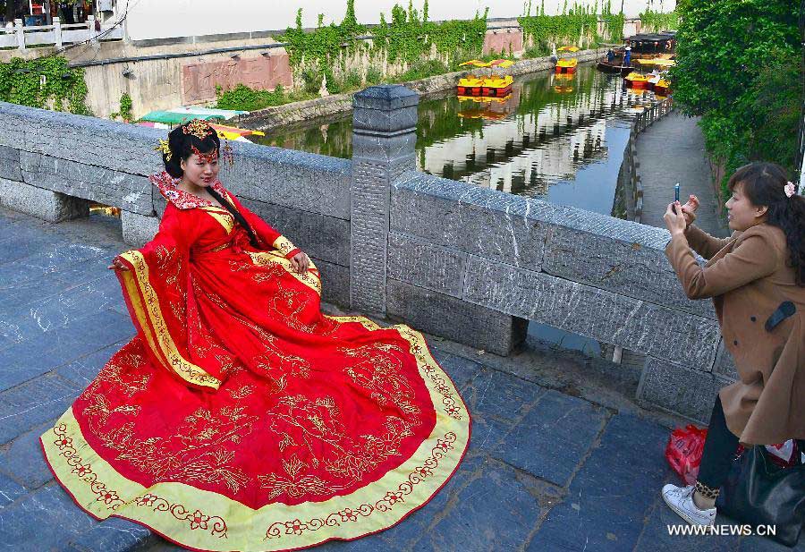 A tourist wearing ancient costume poses for photos on a stone bridge in Sanhe Town of Feixi County, east China's Anhui Province, April 24, 2013. The Sanhe Ancient Town, which has a history of more than 2,500 years, is a typical "ancient town full of rivers and lakes, together with small bridges, flowing water and local dwellings." (Xinhua/Wang Song)