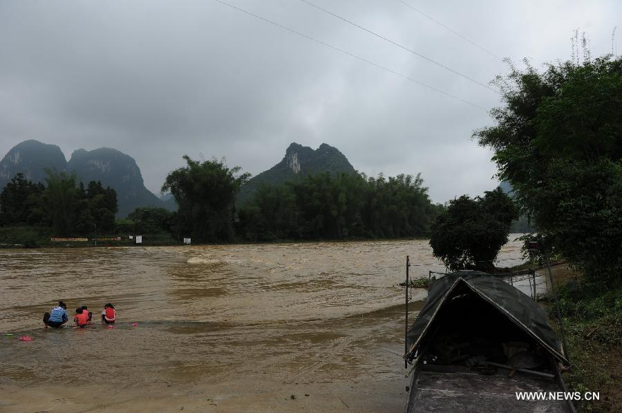 Locals squat at a flooded bank of the Wuyang River in Xiaochang'an Town of southwest China's Guangxi Zhuang Autonomous Region, April 30, 2013. Heavy rainfall hit Guangxi on April 29, making house damaged and causing floods and road cave-ins as well. (Xinhua/Wei Rudai)