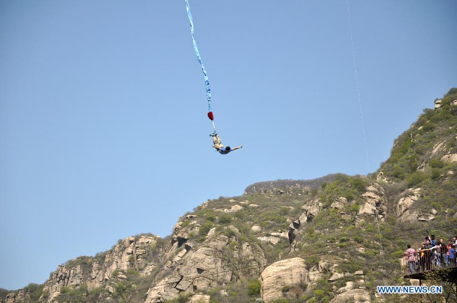 A tourist tries bungee jumping during the three-day May Day holidays at the scenic zone of Qinglong Gorge in Huairou District of Beijing, capital of China, April 30, 2013. (Xinhua/Wang Junfeng)