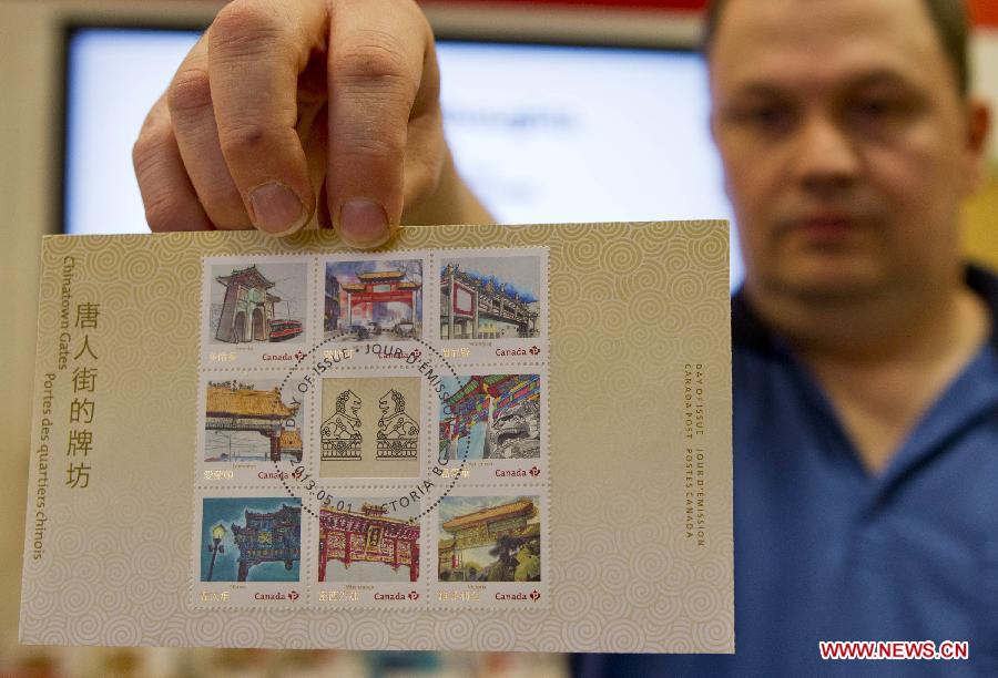 A post office worker shows Chinatown Gates stamps at a post office in Toronto, Canada, May 1, 2013. Canada Post launched a special series of stamps featuring Chinatown gates located in eight cities across the country on Wednesday to highlight the longstanding heritages of Chinese-Canadians. (Xinhua/Zou Zheng)