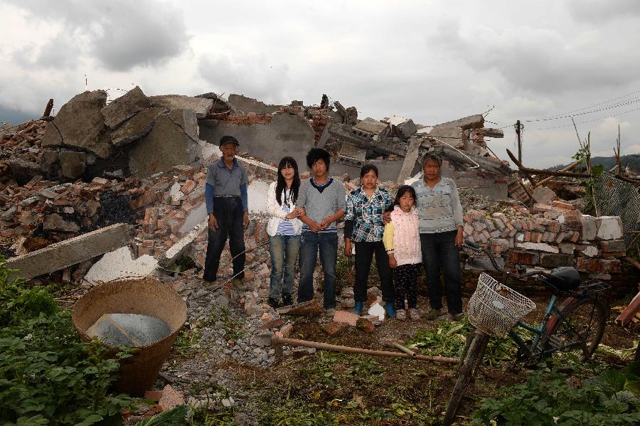 Li Zhenglong (1st R) and his family pose for a photo in front of their dismantled house, which was built in 2009 at a cost of some 100,000 yuan (about 16,234 U.S. dollars), at Longmen Township in quake-hit Lushan County, southwest China's Sichuan Province, May 2, 2013. On high alert for secondary disasters, dilapidated houses were dismantled lately after a 7.0-magnitude quake hit Lushan on April 20.(Xinhua/Jin Liangkuai)