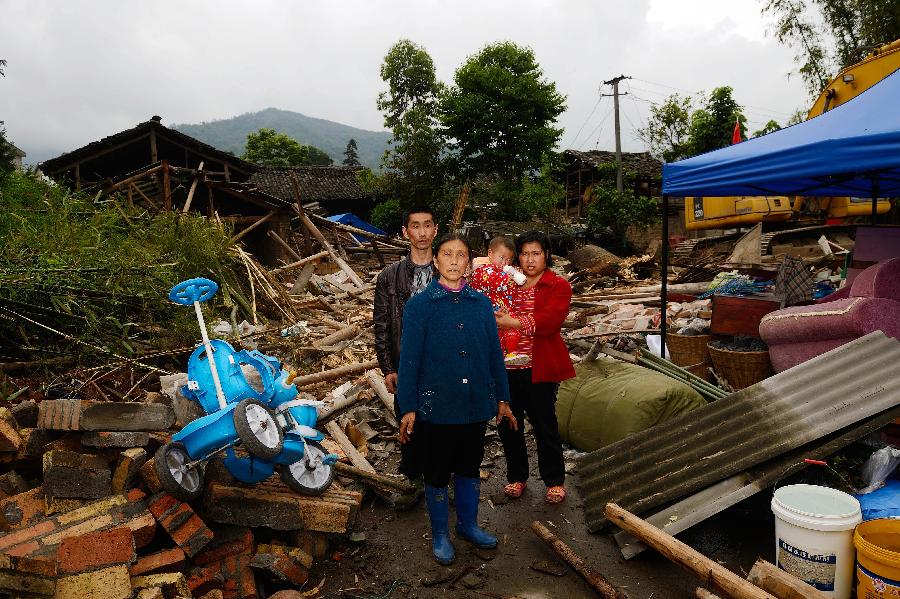 Xiong Zhiquan (1st L) and his family pose for a photo in front of their dismantled house, where they have lived for more than 20 years, at Longmen Township in quake-hit Lushan County, southwest China's Sichuan Province, May 2, 2013. On high alert for secondary disasters, dilapidated houses were dismantled lately after a 7.0-magnitude quake hit Lushan on April 20.(Xinhua/Jin Liangkuai)