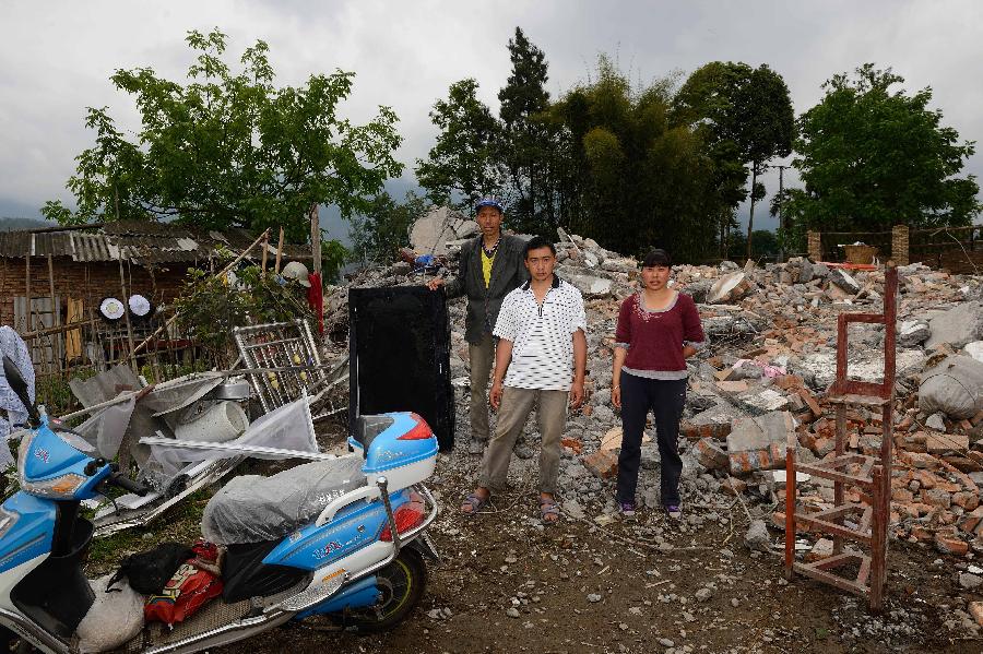 Wei Chunqiang (C) and his family pose for a photo in front of their dismantled house, which was built in 2011 at a cost of some 200,000 yuan (about 32,468 U.S. dollars), at Longmen Township in quake-hit Lushan County, southwest China's Sichuan Province, May 2, 2013. On high alert for secondary disasters, dilapidated houses were dismantled lately after a 7.0-magnitude quake hit Lushan on April 20.(Xinhua/Jin Liangkuai)