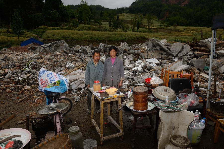 Gao Yongjian and his sister Gao Yonghui pose for a photo in front of their dismantled house, which was built in 1992 at a cost of some 30,000 yuan (about 4,870 U.S. dollars), at Longmen Township in quake-hit Lushan County, southwest China's Sichuan Province, May 2, 2013. On high alert for secondary disasters, dilapidated houses were dismantled lately after a 7.0-magnitude quake hit Lushan on April 20.(Xinhua/Jin Liangkuai)