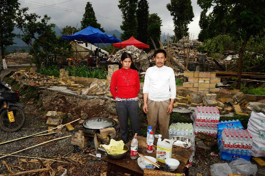 Zhang Tibing and his wife Wang Fengying pose for a photo in front of their dismantled house, which was built in 1997 at a cost of some 50,000 yuan (about 8,117 U.S. dollars), at Longmen Township in quake-hit Lushan County, southwest China's Sichuan Province, May 2, 2013. On high alert for secondary disasters, dilapidated houses were dismantled lately after a 7.0-magnitude quake hit Lushan on April 20.(Xinhua/Jin Liangkuai)