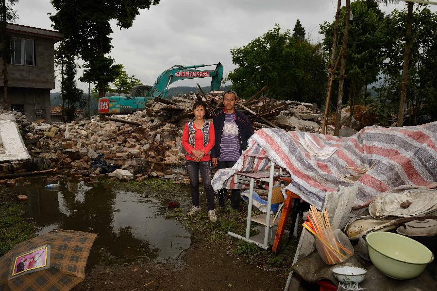 Song Jianqiang and his wife Wang Guolan pose for a photo in front of their dismantled house, which was built in 1998 at a cost of some 60,000 yuan (about 9,740 U.S. dollars), at Longmen Township in quake-hit Lushan County, southwest China's Sichuan Province, May 2, 2013. On high alert for secondary disasters, dilapidated houses were dismantled lately after a 7.0-magnitude quake hit Lushan on April 20.(Xinhua/Jin Liangkuai)