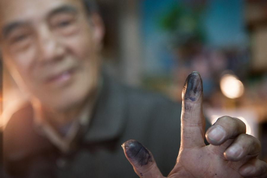 Zhang Guangyi shows his ink-stained fingers at his shop in Beijing, capital of China, April 26, 2013.  (Xinhua/Xu Zijian)
