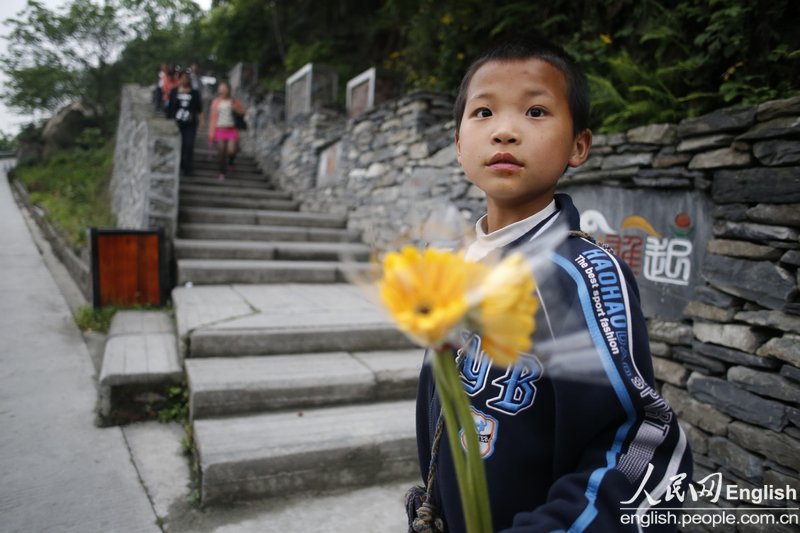 A little boy sells chrysanthemums outside the Wenchuan Earthquake Memorial in Wenchuan of Sichuan on April 29, 2013. (Photo/CFP) 