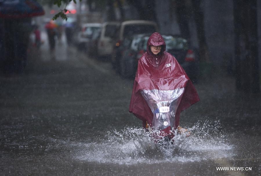 A woman rides in rain on a waterlogged road in Nanchang, capital of east China's Jiangxi Province, May 15, 2013. A heavy rainfall hit Nanchang overnight. (Xinhua/Zhou Mi) 