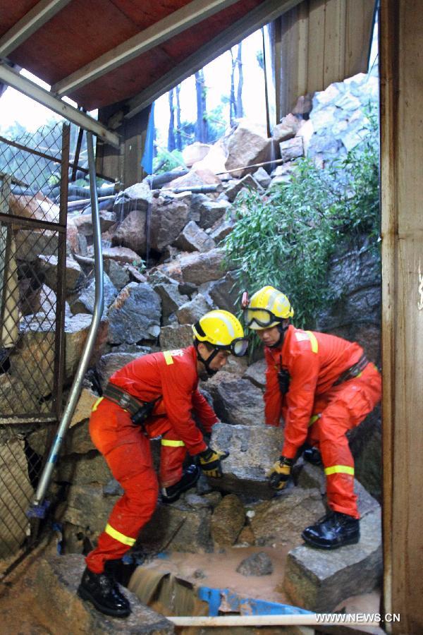 Rescuers try to carry away a rock at the site of a landslide in Xiamen, southeast China's Fujian Province, May 16, 2013. Torrential rainfall triggered a landslide at the Qianpu Flea Market in Xiamen early May 16, causing one adult and two children dead. (Xinhua/Zeng Demeng)  