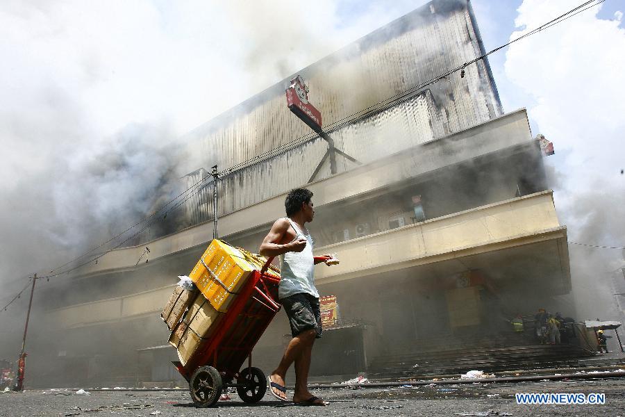 A man evacuates from the fire accident site in Manila, the Philippines, May 16, 2013. Two people were rescued from the fire, as firefighters estimate the fire may last for two days. (Xinhua/Rouelle Umali) 
