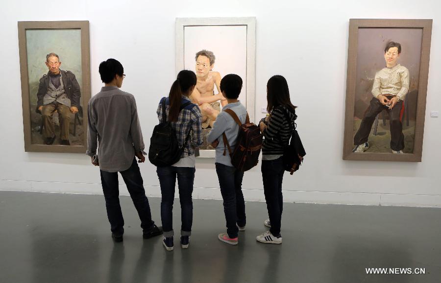 Visitors gather to watch oil paintings at an exhibition of Chinese realistic painter Xin Dongwang's works in Beijing, capital of China, May 17, 2013. (Xinhua/Zhang Yanhui)