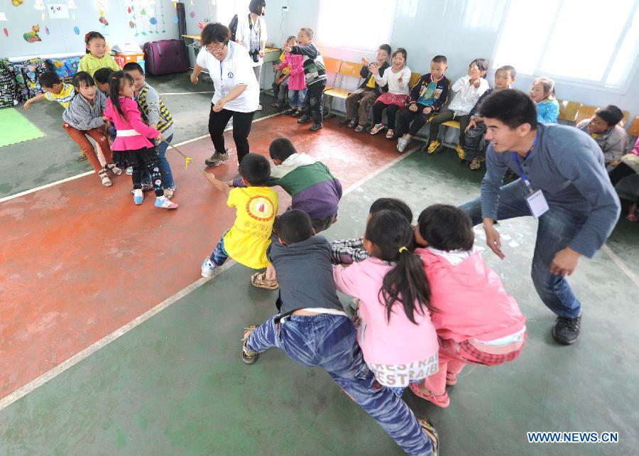 Psychological aid volunteers play game with children at a psychological support workstation set up by the Chinese Academy of Sciences (CAS) in a makeshift school in the quake-hit Lushan County, southwest China's Sichuan Province, May 14, 2013. (Xinhua/Li Xiaoguo) 