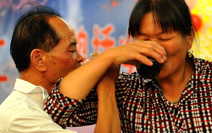Zhao Dangjun, 60, drinks beer with his wife at a dinning party to welcome newcomers in Zhengzhou, Henan province. (Photo/ Guangming Online)