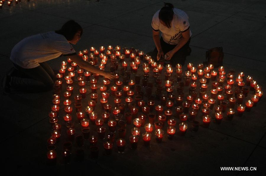 People light candles during a commemoration event for the people that died on consequence of Human Immunodeficiency Virus (HIV), organized by the Atlacatl Association Vivo Positivo, at the Salvador del Mundo Square, in San Salvador, capital of El Salvador, on May 19, 2013. A total of 4,000 candles were lit during the event. (Xinhua/Oscar Rivera)