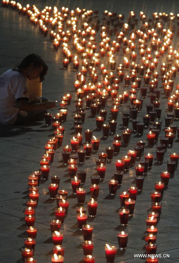 A girl lights candles during a commemoration event for the people that died on consequence of Human Immunodeficiency Virus (HIV), organized by the Atlacatl Association Vivo Positivo, at the Salvador del Mundo Square, in San Salvador, capital of El Salvador, on May 19, 2013. A total of 4,000 candles were lit during the event. (Xinhua/Oscar Rivera)