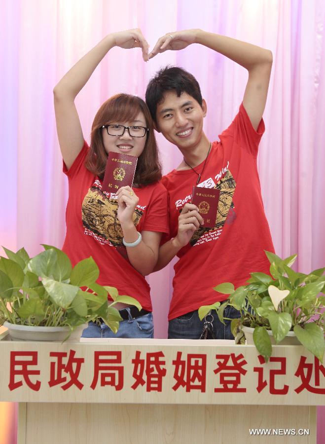 A bride and a bridegroom pose for photos after registering as a married couple in the registry of marriages in Sanya City, south China's Hainan Province, May 20, 2013. As the pronunciation of the date number "520" sounds like "I love you" in Chinese, many people chose to register as couples on Monday. (Xinhua/Chen Wenwu)