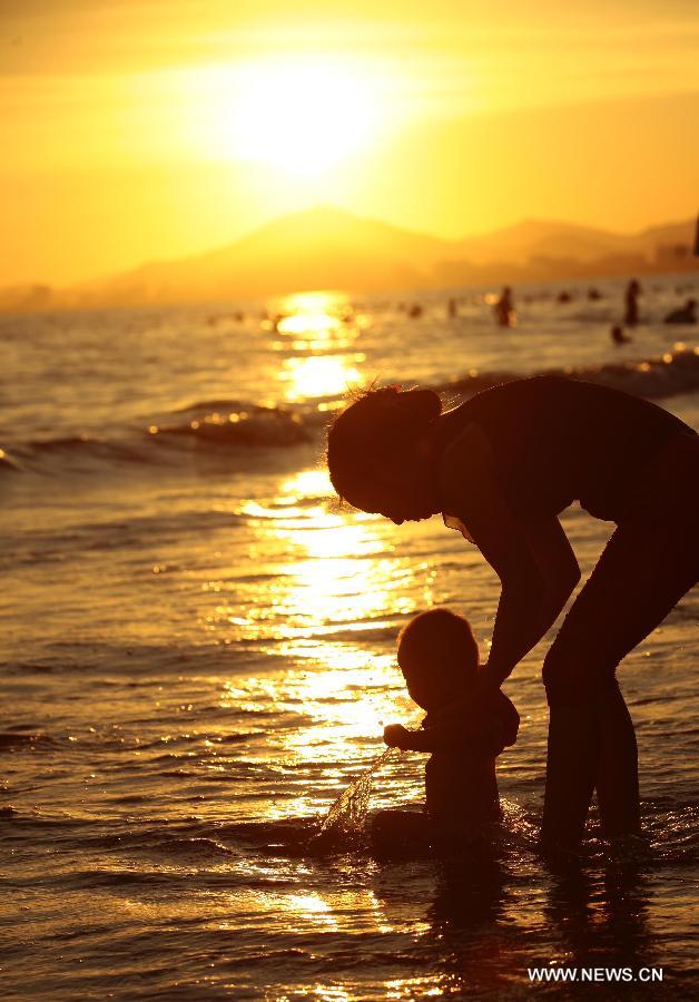 A woman takes a child playing along the seaside in Sanya, south China's Hainan Province, May 20, 2013. (Xinhua/Chen Wenwu)