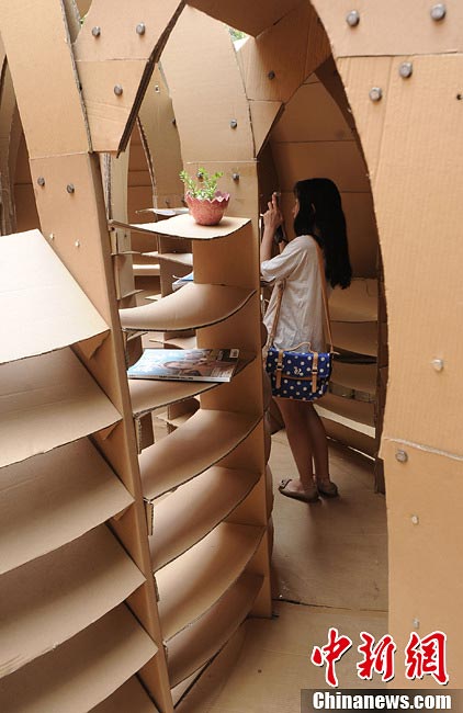 A student takes pictures inside a house made of paper boxes at Chongqing University in Southwest China's Chongqing Municipality, May 20, 2013. (CNS/Chen Chao)